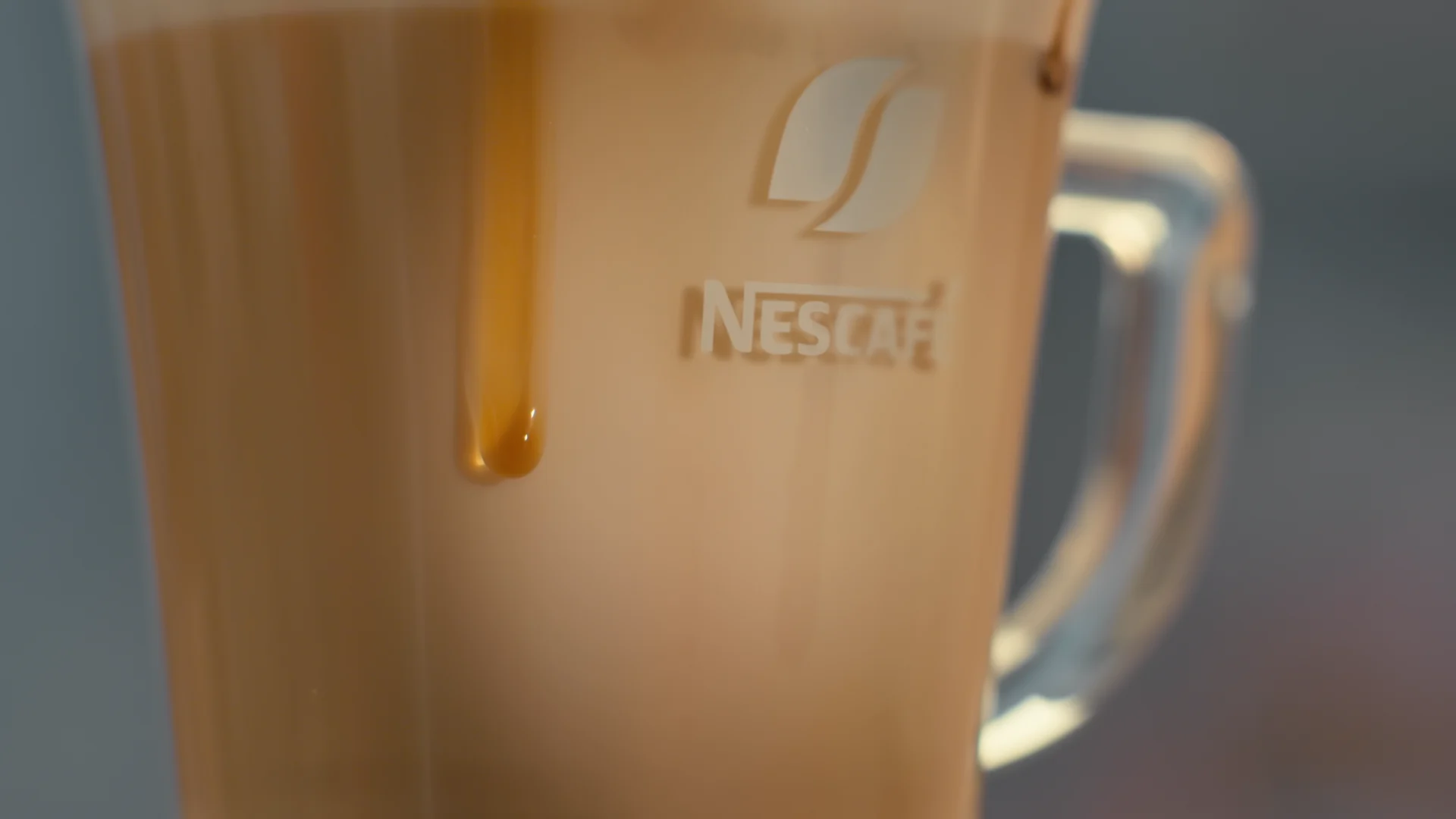 NESCAFÉ glass mug with coffee drips running over the logo, after